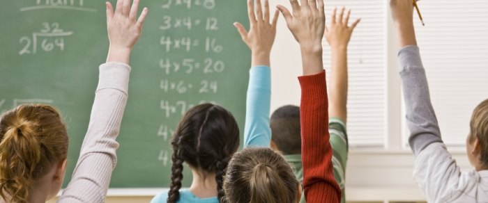 Children with their hands raised in a classroom