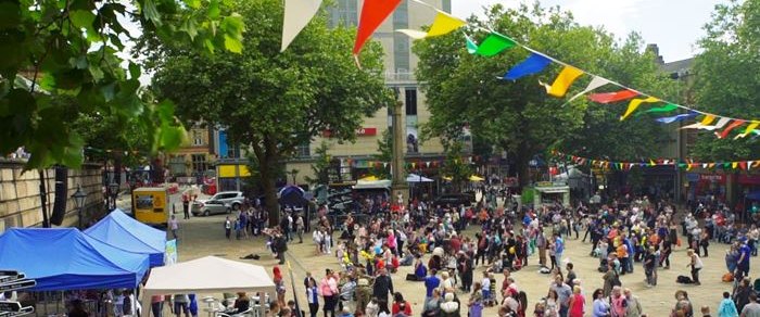 Market stalls and bunting on the Flag Market in Preston with a crowd