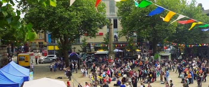 Market stalls and bunting on the Flag Market in Preston with a crowd