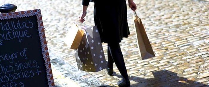 A shopper carrying bags along a paved Preston street