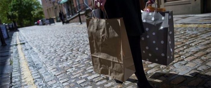 A shopper carrying bags along a paved street