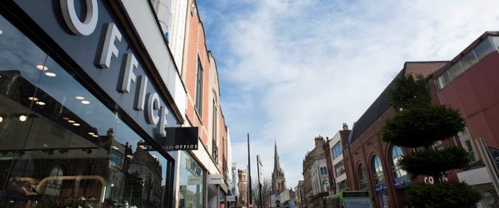 Shopfronts on Fishergate in Preston with the street receding towards the station
